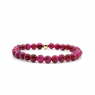 A beaded stretch bracelet featuring round magenta and deep red beads with a small polished gold spacer bead, displayed on a clean white background.