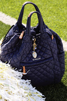 Quilted navy handbag with 'Me Wallace' tag on grass